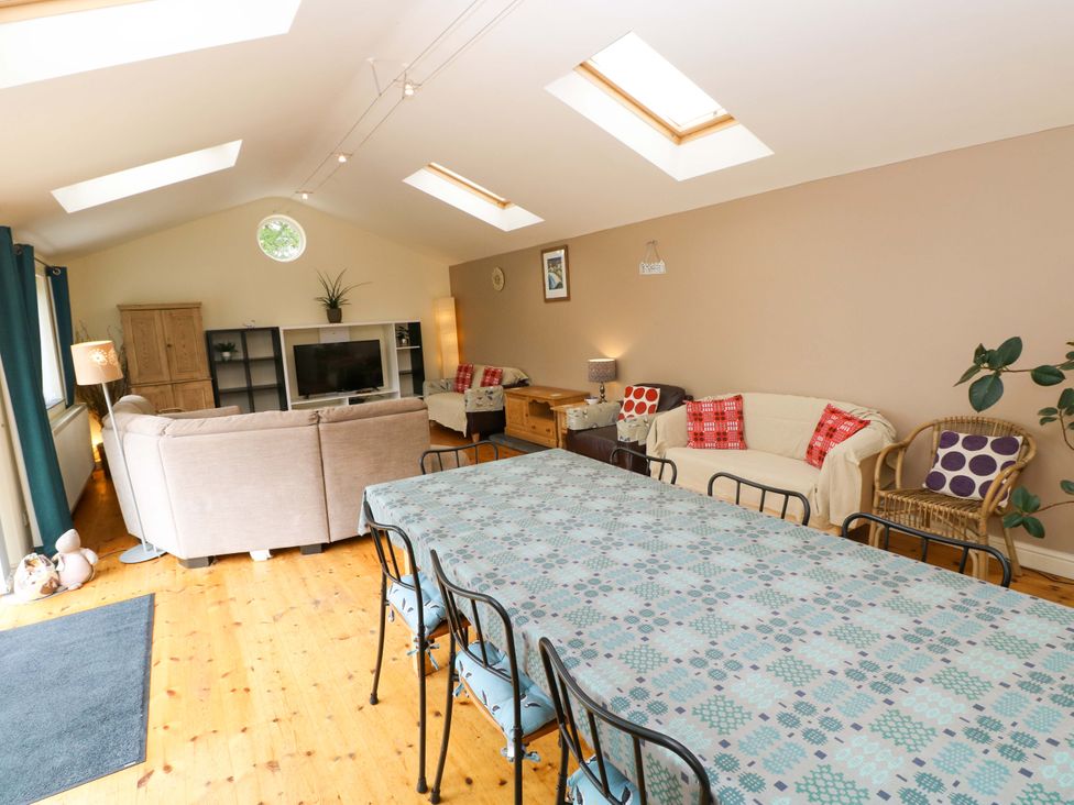 A living room with a dining table and sofas at Greenbanks in Dinas Cross, Pembrokeshire