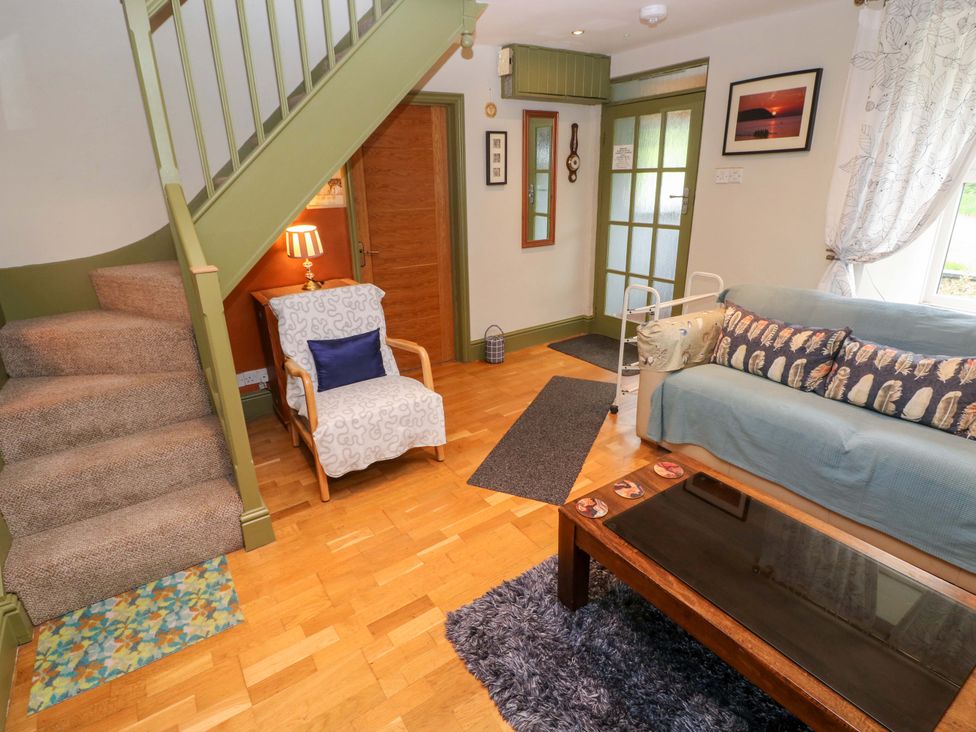 A living room with a couch and a staircase at Greenbanks in Dinas Cross, Pembrokeshire