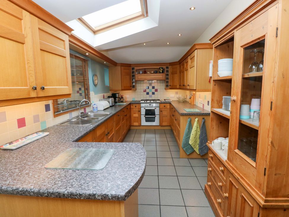 A kitchen with wooden cabinets and a countertop at Greenbanks, Dinas Cross, Pembrokeshire