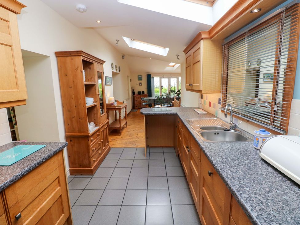 A kitchen with cabinets and a dining area at Greenbanks, Dinas Cross, Pembrokeshire