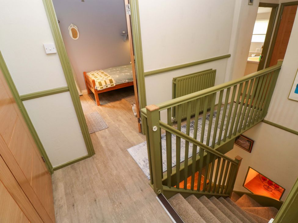 A hallway with a staircase and a door to a bedroom at Greenbanks in Dinas Cross, Pembrokeshire