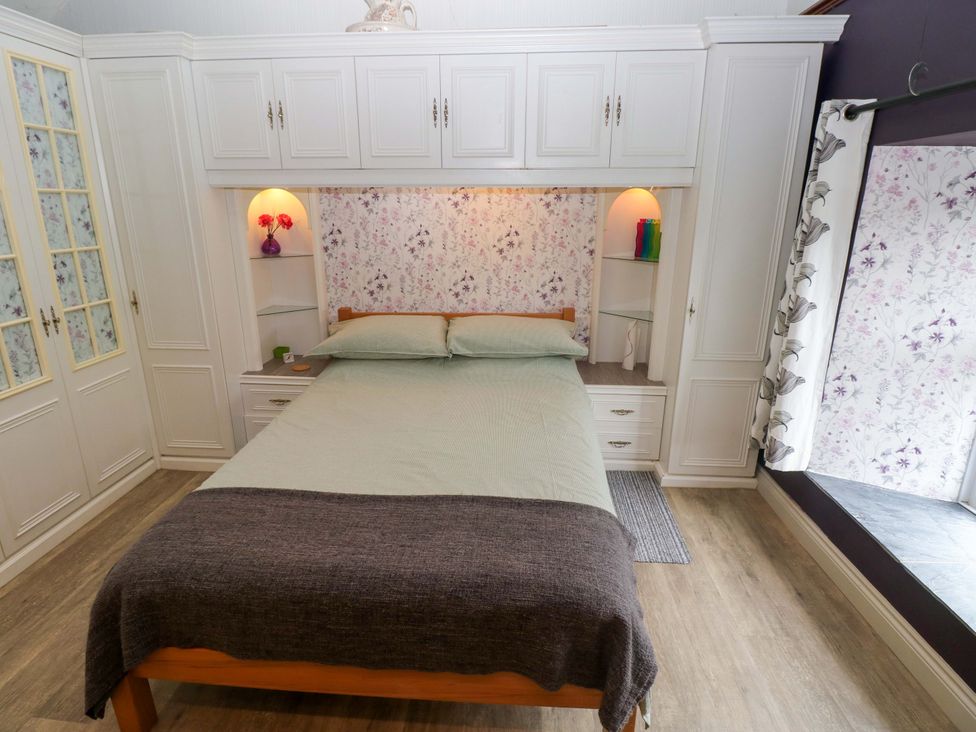 A bedroom with a bed and wardrobe at Greenbanks in Dinas Cross, Pembrokeshire