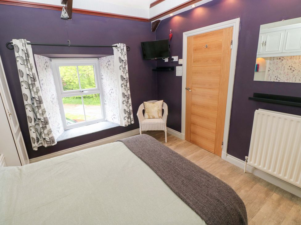 A bedroom with a bed, window, and a chair at Greenbanks in Dinas Cross, Pembrokeshire