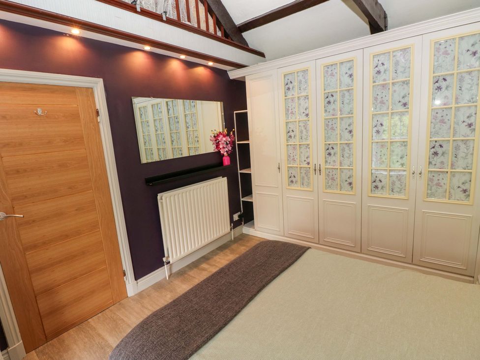 A bedroom with a wardrobe, mirror, and radiator at Greenbanks, Dinas Cross, Pembrokeshire