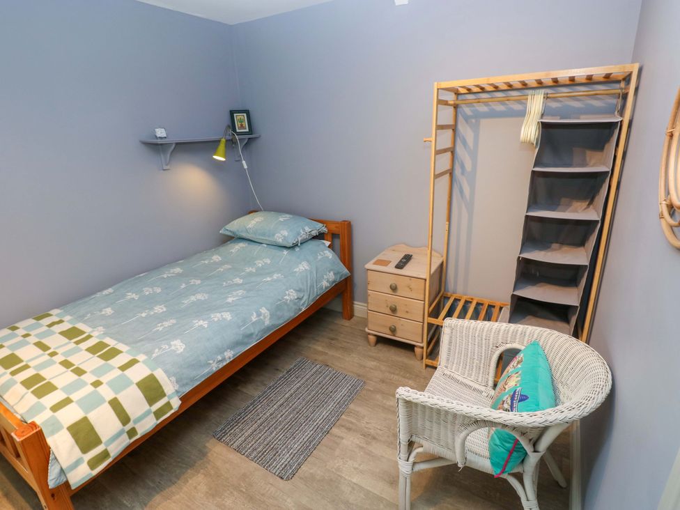 A bedroom with a bed and chair at Greenbanks in Dinas Cross, Pembrokeshire