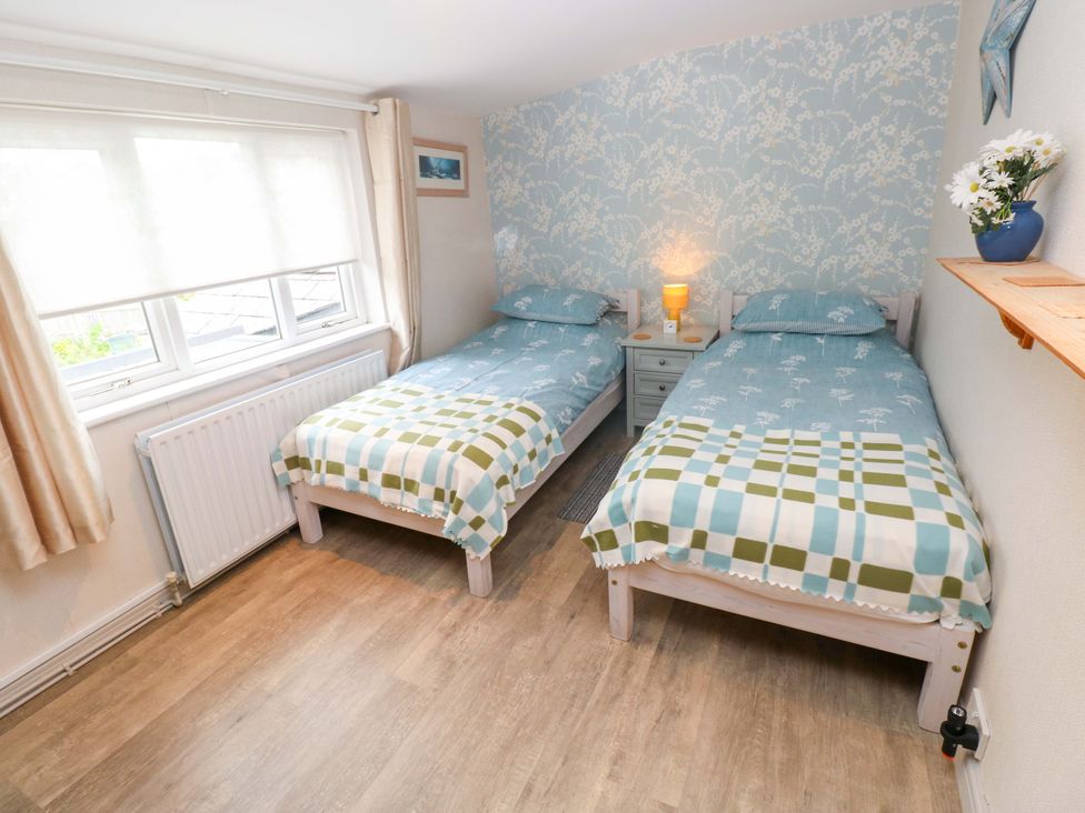 A bedroom with twin beds and a bedside table at Greenbanks in Dinas Cross, Pembrokeshire