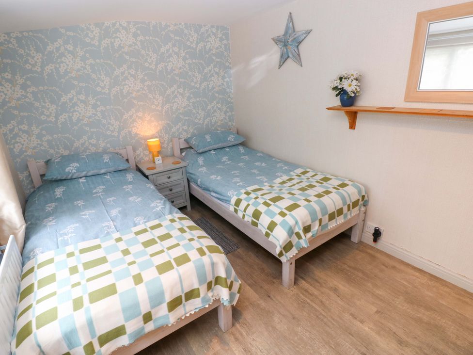 A bedroom with two single beds and a bedside table at Greenbanks in Dinas Cross, Pembrokeshire