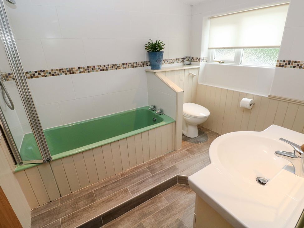 A bathroom with a bathtub, toilet, and sink at Greenbanks Dinas Cross, Pembrokeshire
