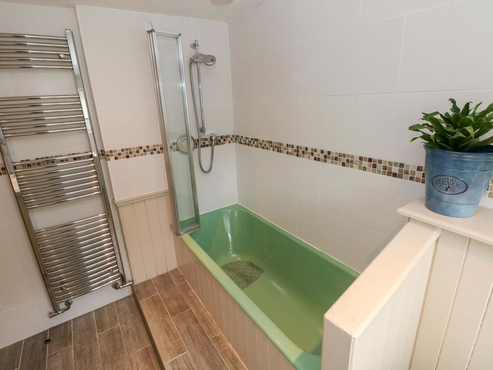A bathroom with a green bathtub and shower at Greenbanks, Dinas Cross, Pembrokeshire