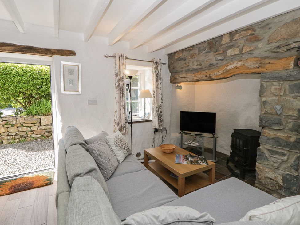 A living room with a sofa, table, television, and lamp at Middle Cottage in Newport, Pembrokeshire