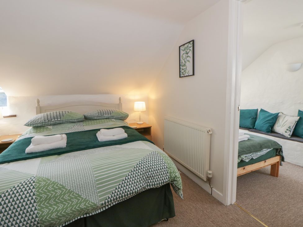 A bedroom with a bed and a seating area at Middle Cottage Newport, Pembrokeshire