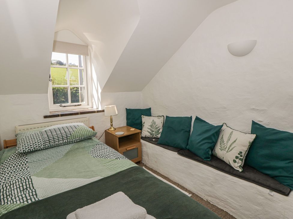 A bedroom with a bed and cushions at Middle Cottage in Newport, Pembrokeshire