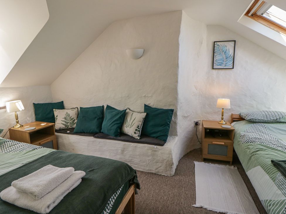 A bedroom with beds and a sitting area at Middle Cottage in Newport, Pembrokeshire