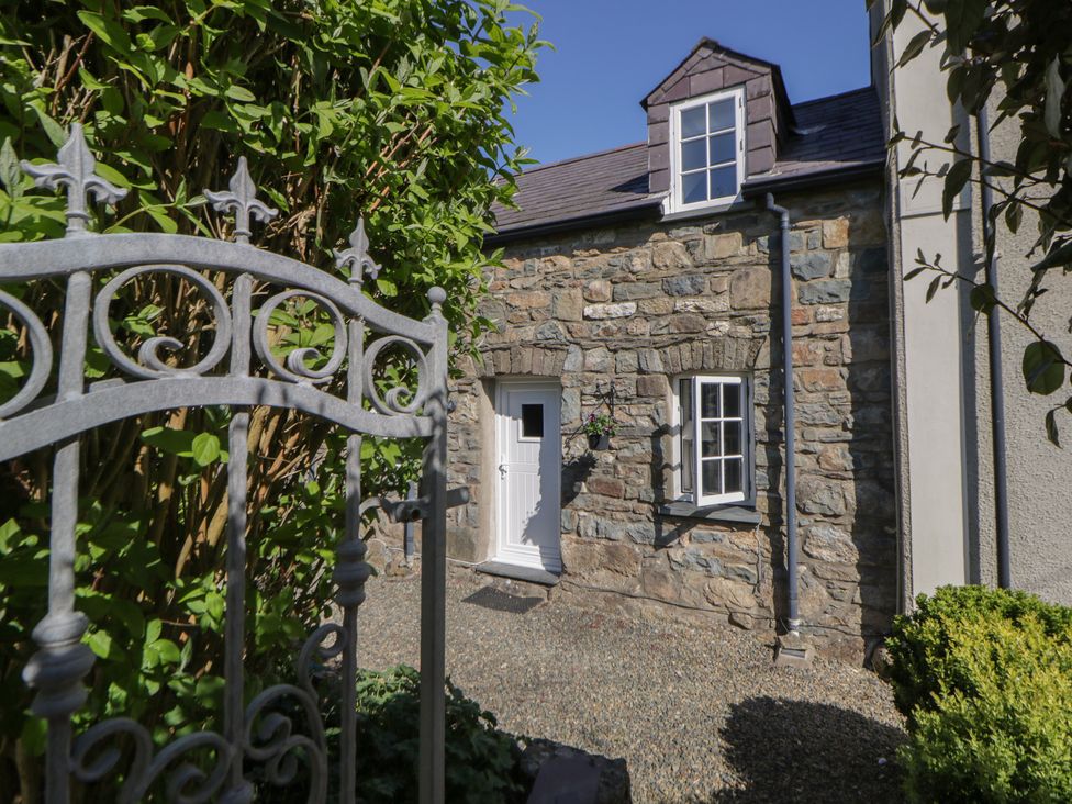 An exterior view of a stone building with a gate and greenery at Middle Cottage Newport, Pembrokeshire