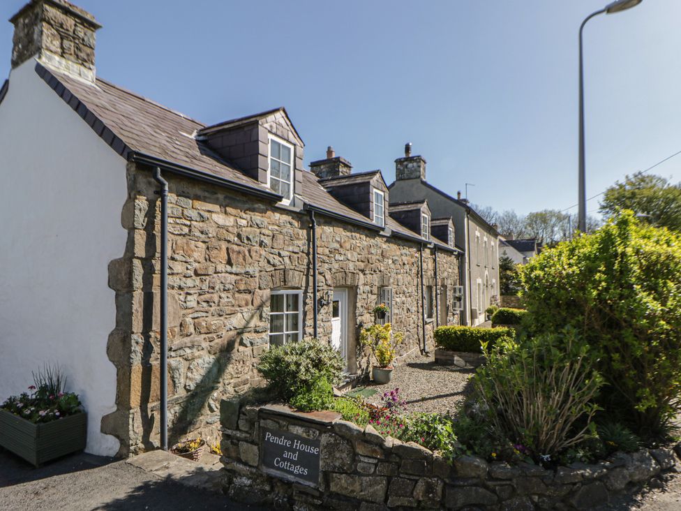 An exterior view of a stone house with garden at Pendre House and Cottages in Newport, Pembrokeshire
