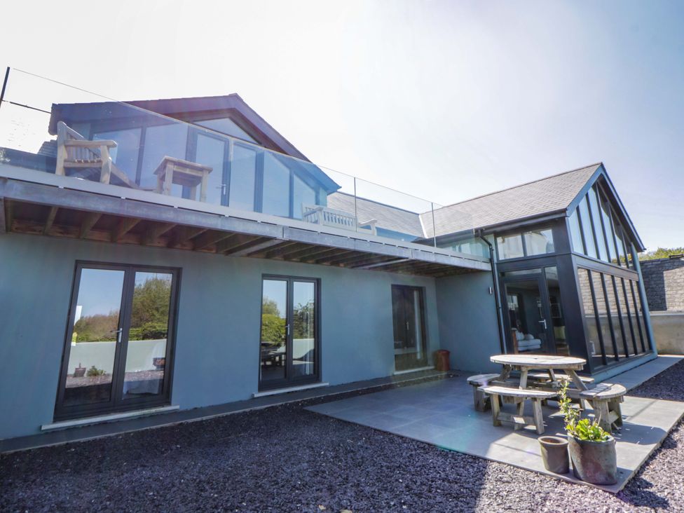 A house with a deck and outdoor table at The Willows in Newport, Pembrokeshire