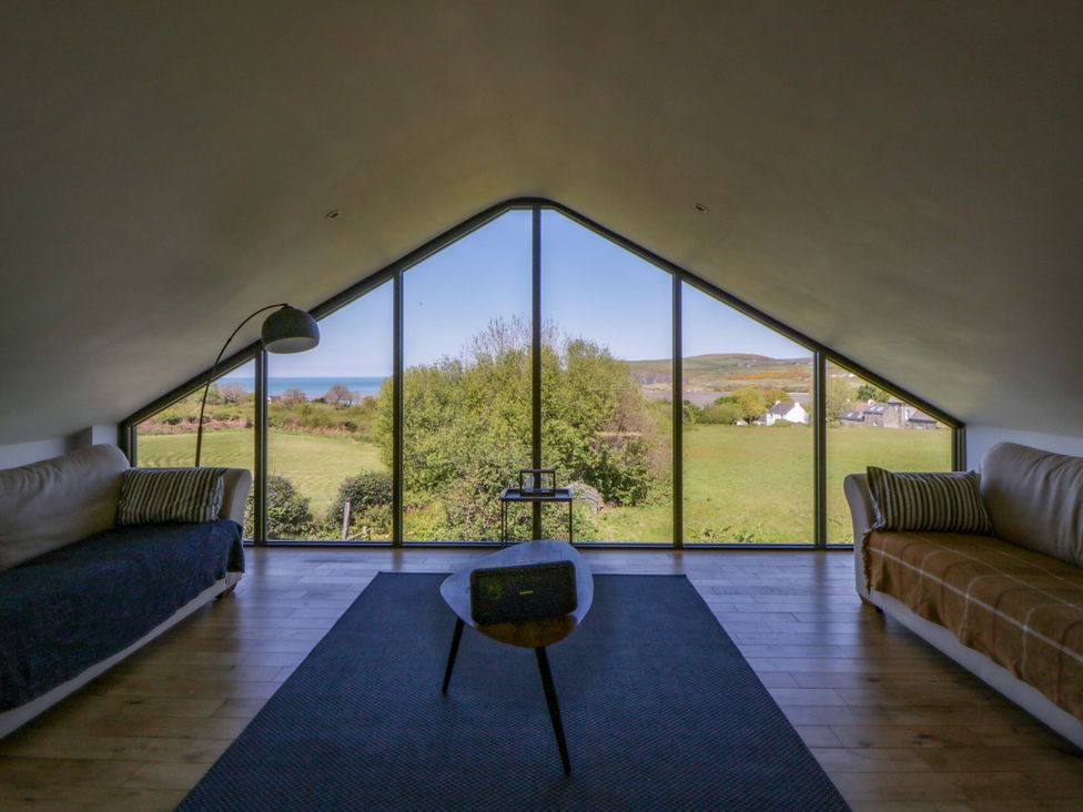 A living room with large windows showing the view at The Willows in Newport, Pembrokeshire