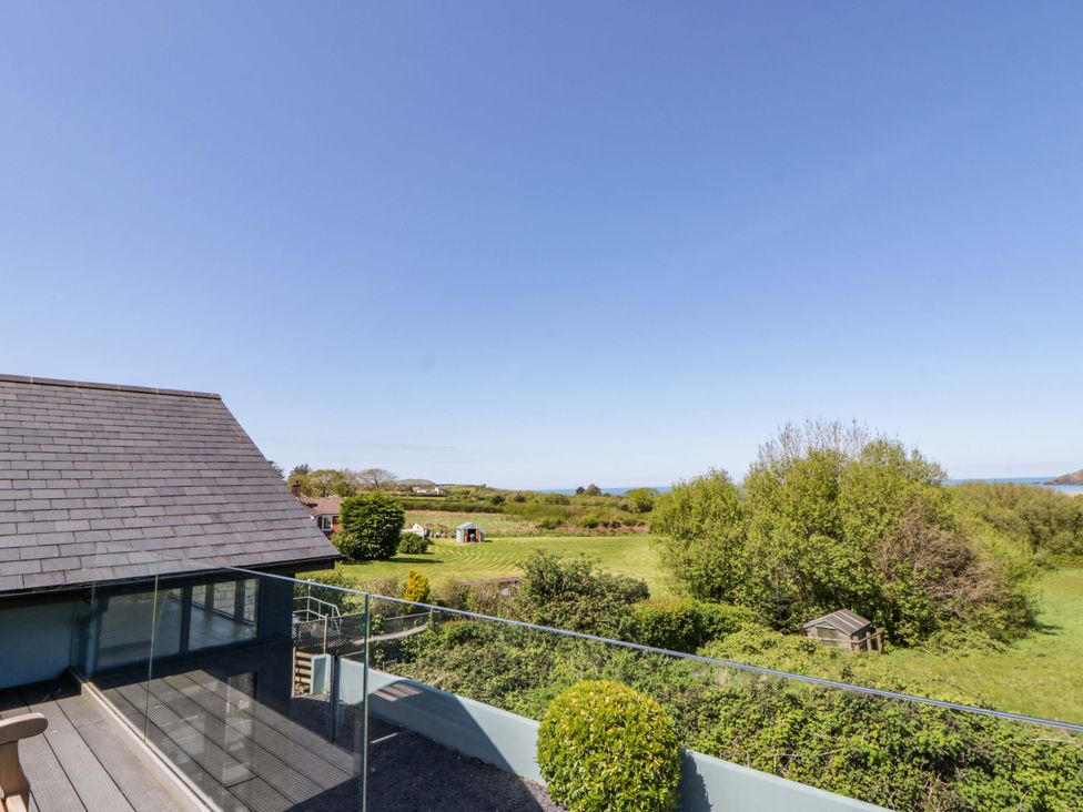 An outdoor balcony view overlooking trees and the sea at The Willows Newport, Pembrokeshire