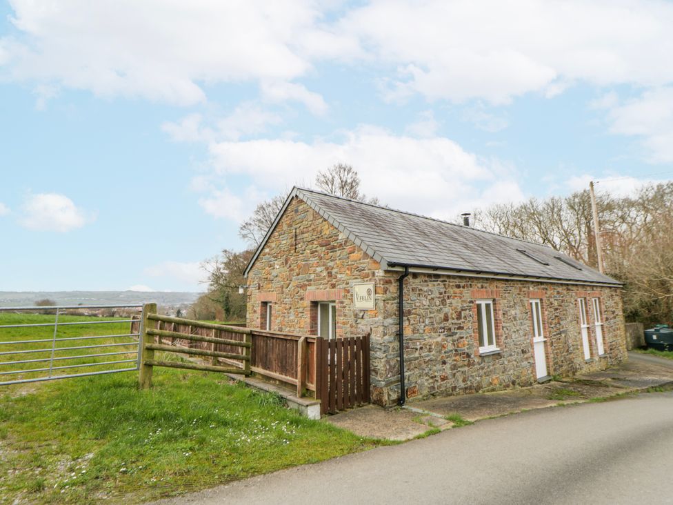 A stone house with a fence and gate at Y Felin in Cardigan, Ceredigion