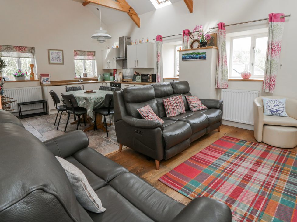 A living room with a sofa and dining area at Y Felin in Cardigan, Ceredigion
