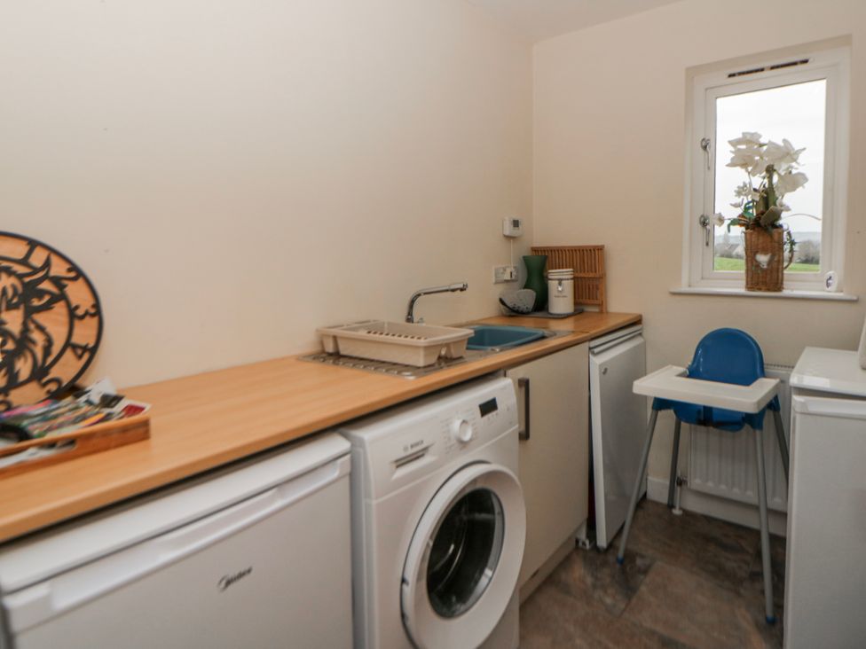 A laundry room with a washing machine and a counter at Y Felin in Cardigan, Ceredigion