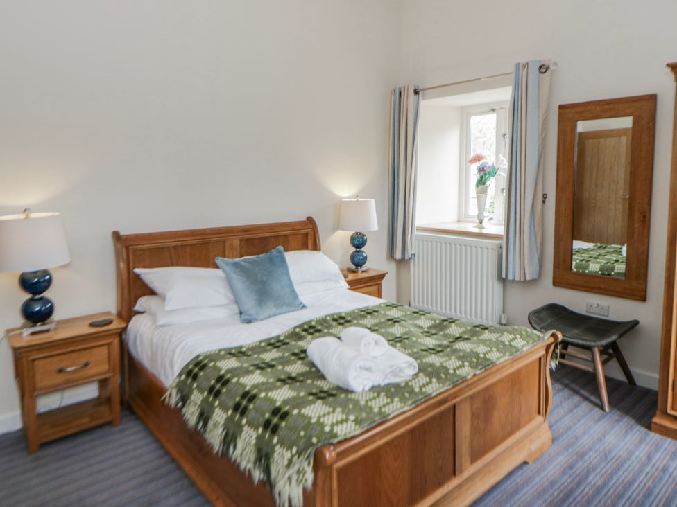 A bedroom with a bed and side tables at Y Felin in Cardigan, Ceredigion