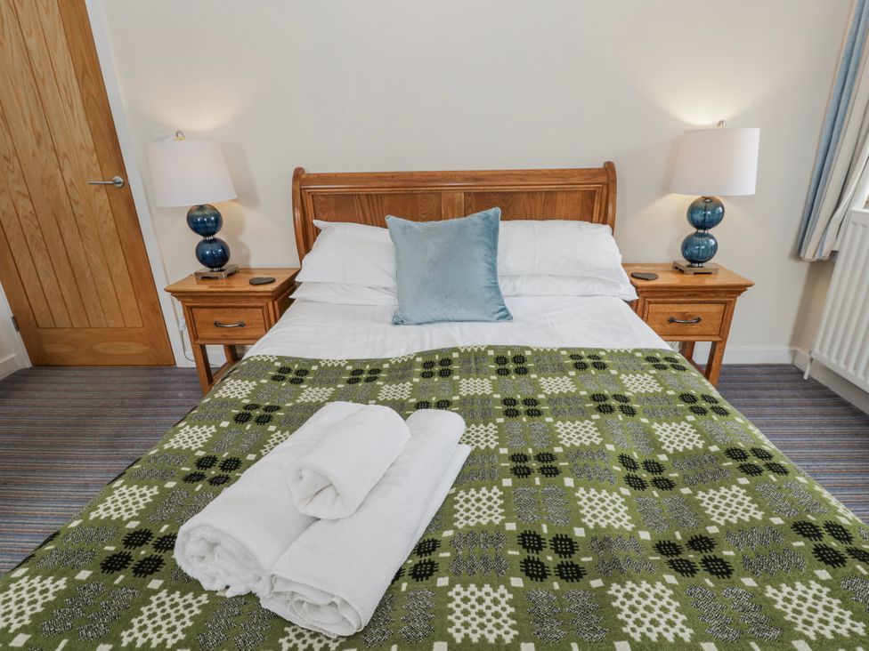 A bedroom with a bed and bedside tables at Y Felin in Cardigan, Ceredigion