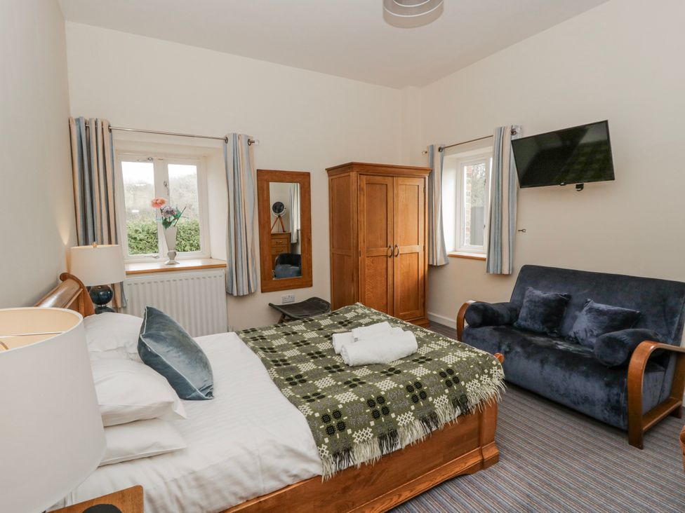 A bedroom with a bed and a sofa at Y Felin in Cardigan, Ceredigion