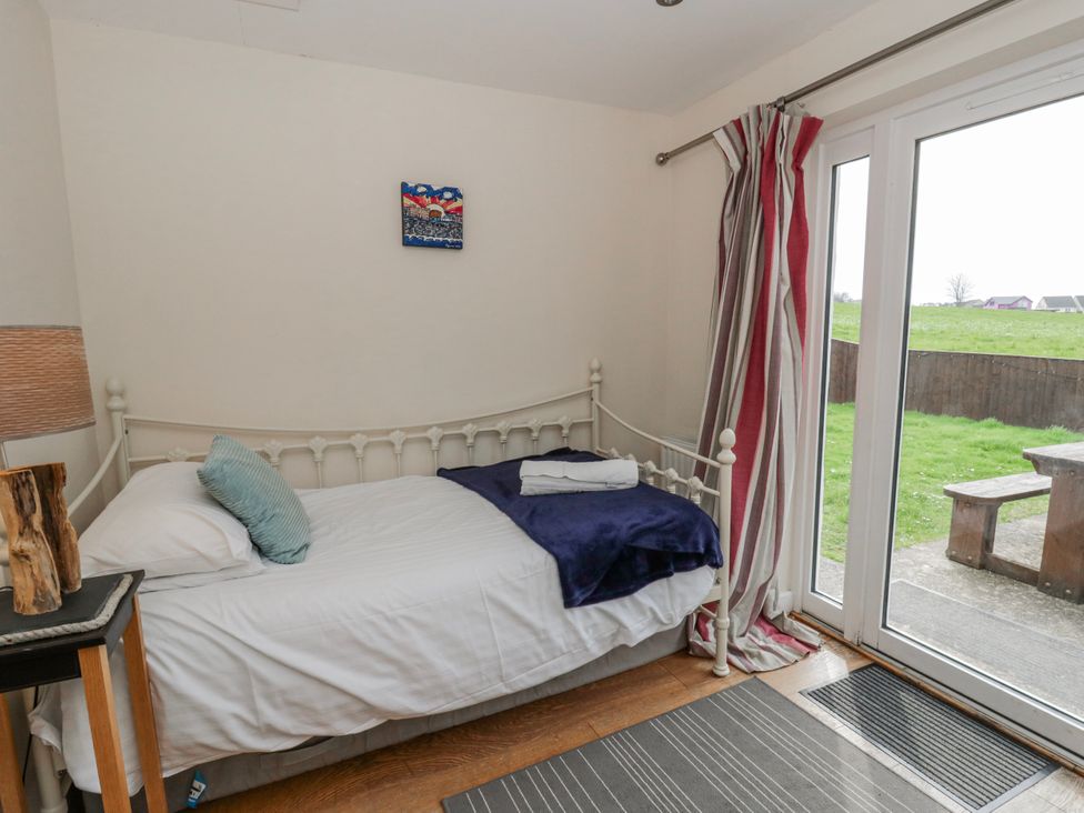 A bedroom with a bed and door leading to outdoor space at Y Felin in Cardigan, Ceredigion
