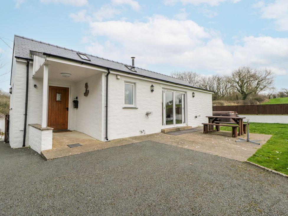 An outdoor view of a house with a table and bench at Y Felin, Cardigan, Ceredigion