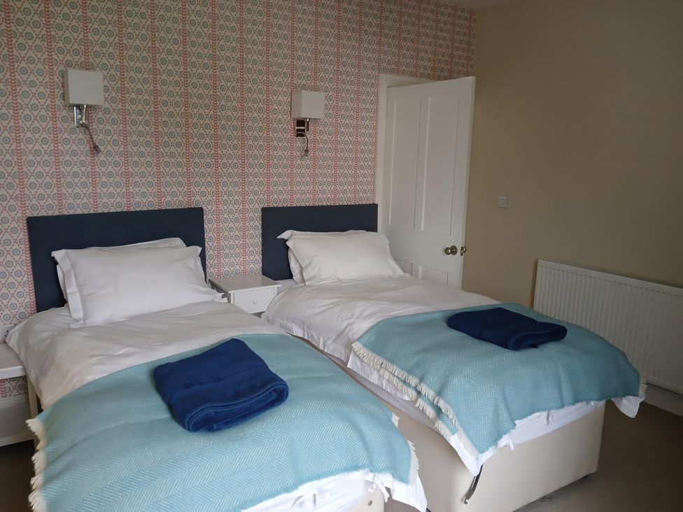 A bedroom with twin beds and a nightstand at Lyndale in Newport, Pembrokeshire