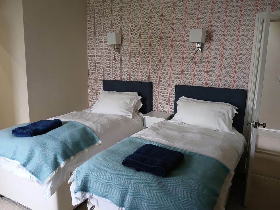 A bedroom with two beds and a bedside table at Lyndale in Newport, Pembrokeshire