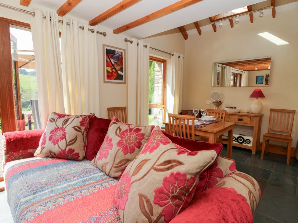 A living room with a sofa and dining area at Dan Castell Cottage in Llandeilo, Carmarthenshire