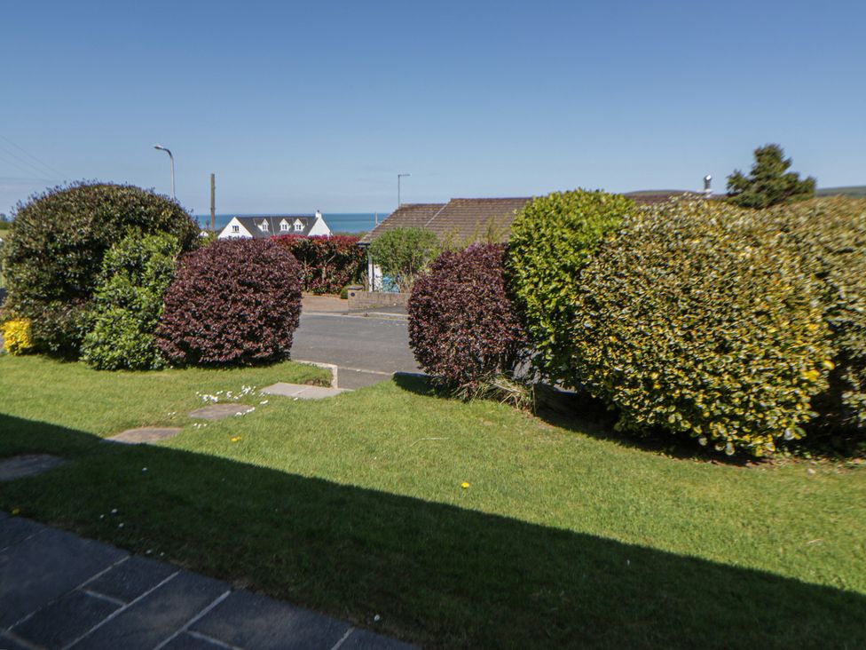 A view of bushes and grass with houses and sea in the background at Dolwylan Newport, Pembrokeshire