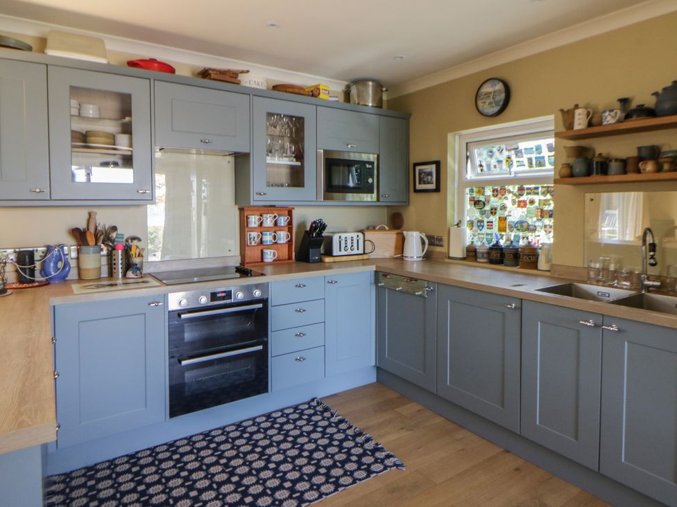 A kitchen with cabinets, sink, and oven at Dolwylan, Newport, Pembrokeshire