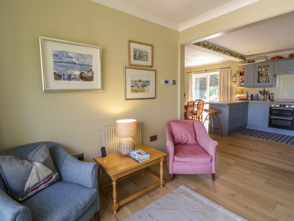 A living room with a sofa and armchair leading to the kitchen at Dolwylan in Newport, Pembrokeshire
