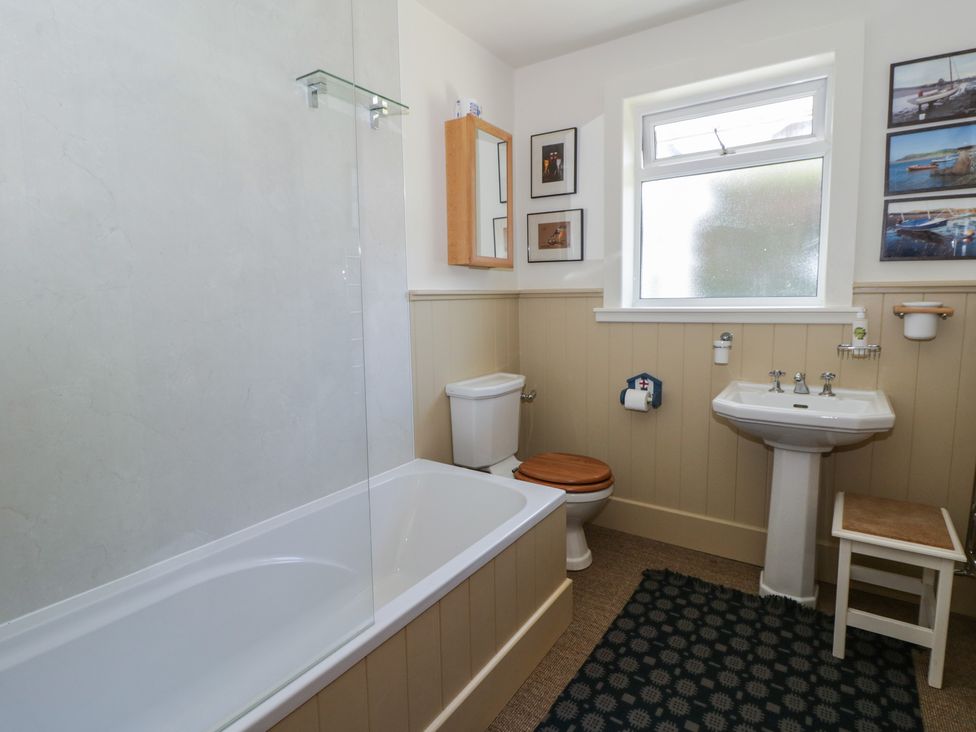 A bathroom with a bathtub, toilet, sink, and wall pictures at Dolwylan Newport, Pembrokeshire