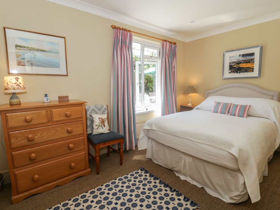 A bedroom with a bed, dresser, and chair at Dolwylan, Newport, Pembrokeshire