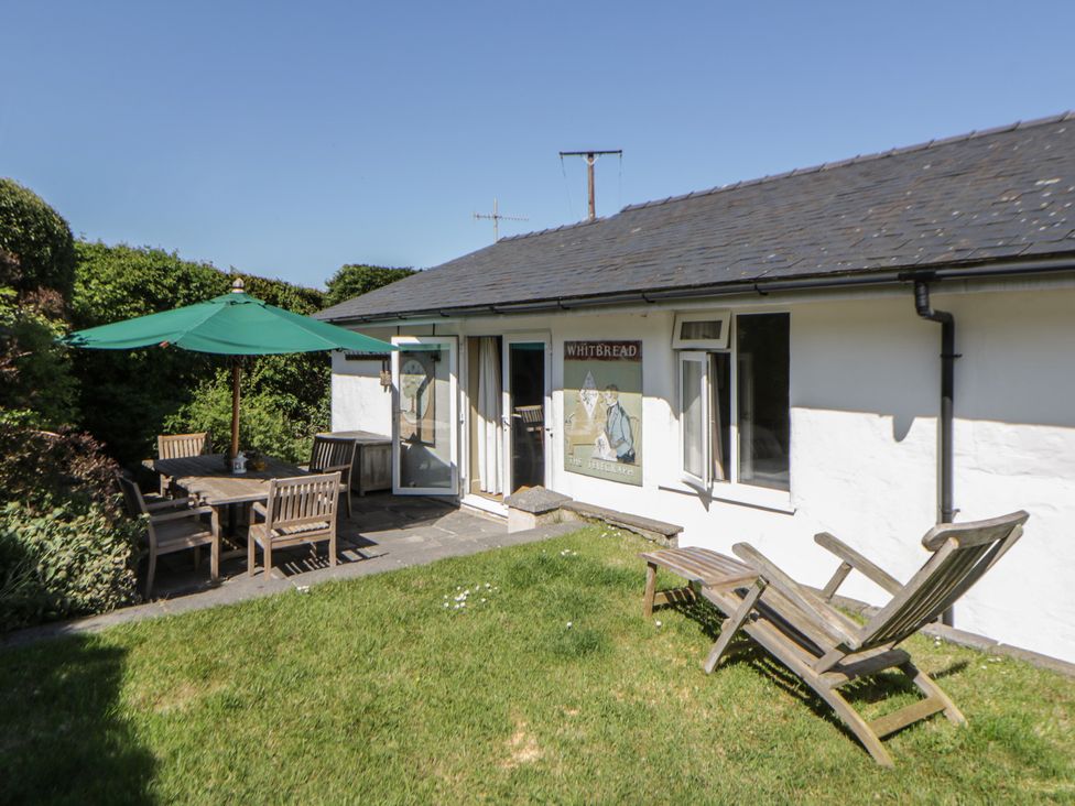A garden with a table and chairs under an umbrella at Dolwylan Newport, Pembrokeshire