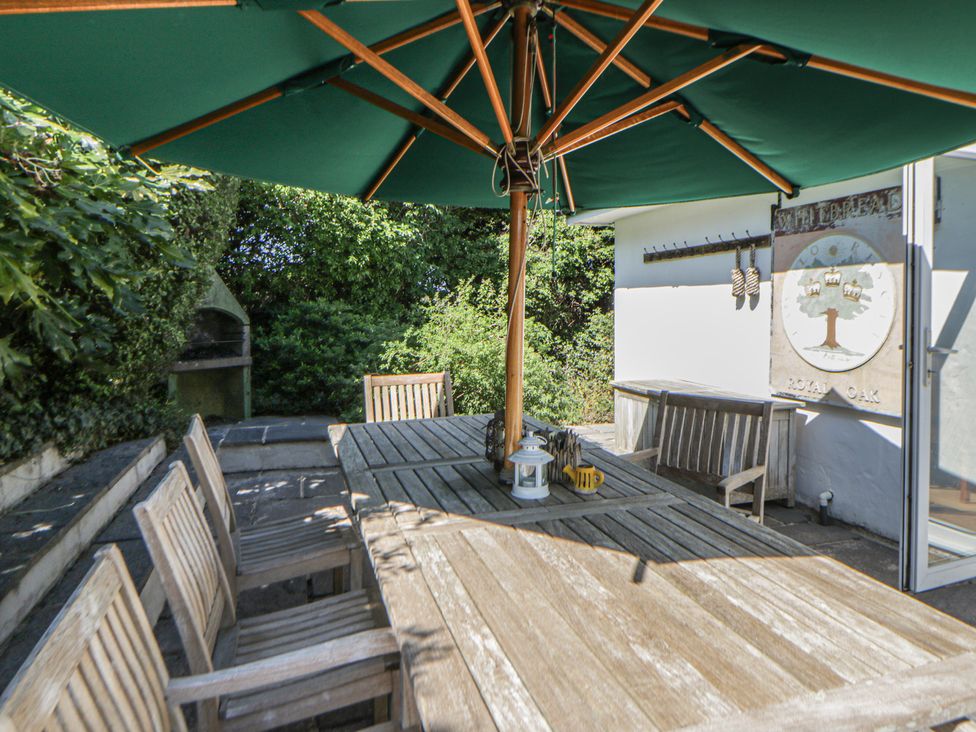 An outdoor eating area with a table and chairs under an umbrella at Dolwylan in Newport, Pembrokeshire