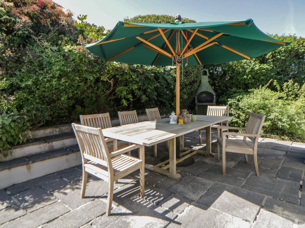 An outdoor dining area with a table and chairs under an umbrella at Dolwylan, Newport, Pembrokeshire
