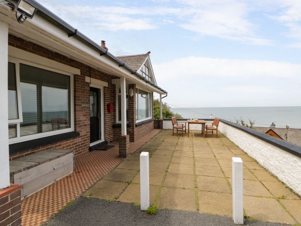 An outdoor patio with a table and chairs overlooking the sea at Delyn Aur, Tresaith, Ceredigion
