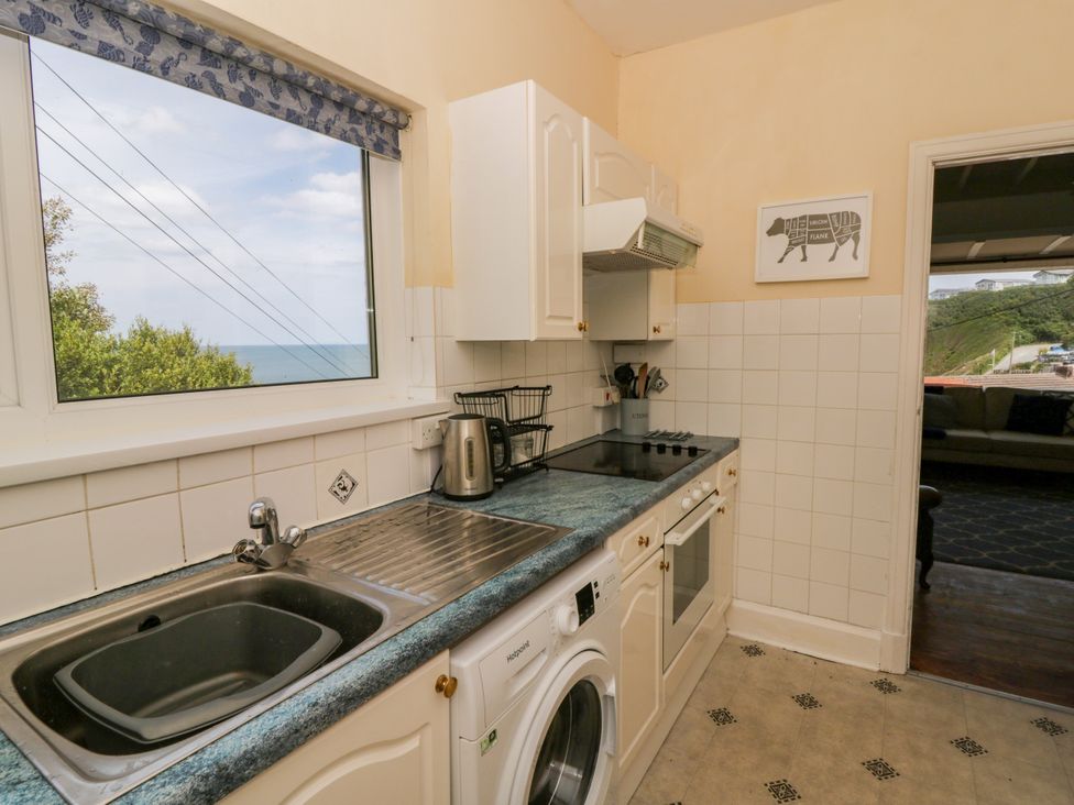 A kitchen with sink, cooker, and window at Delyn Aur, Tresaith, Ceredigion