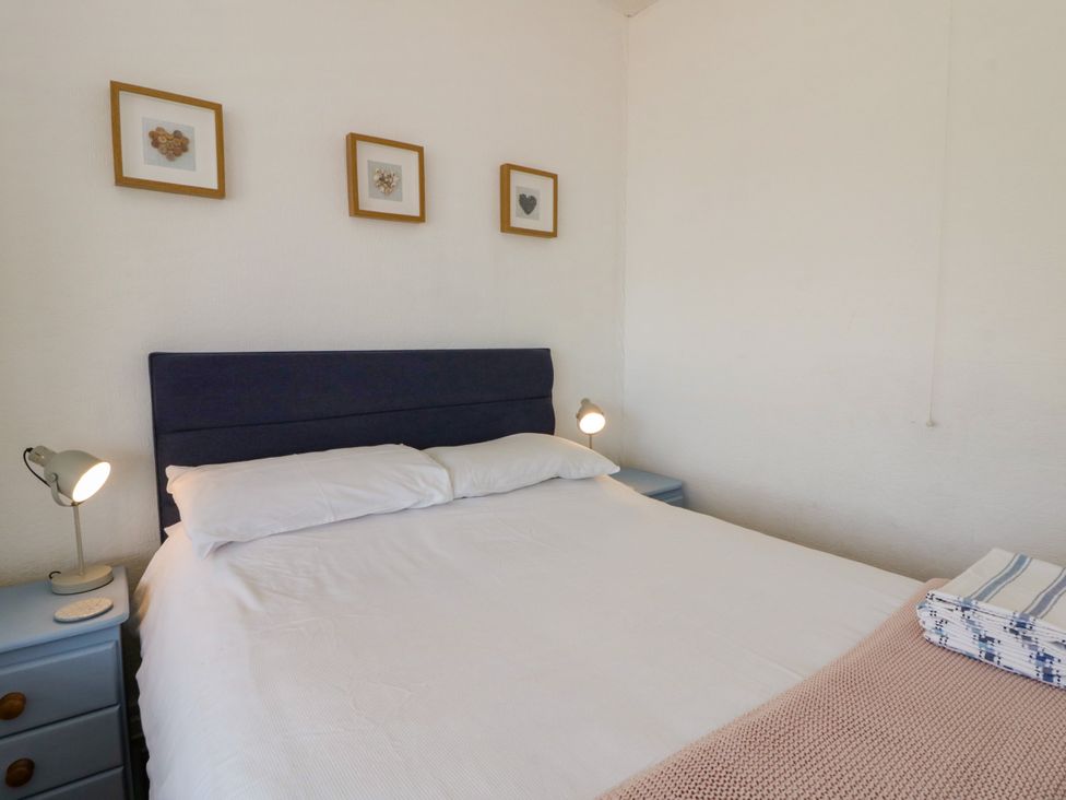 A bedroom with a bed and bedside lamp at Delyn Aur, Tresaith, Ceredigion