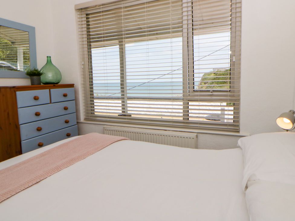 A bedroom with a window and dresser at Delyn Aur Tresaith, Ceredigion