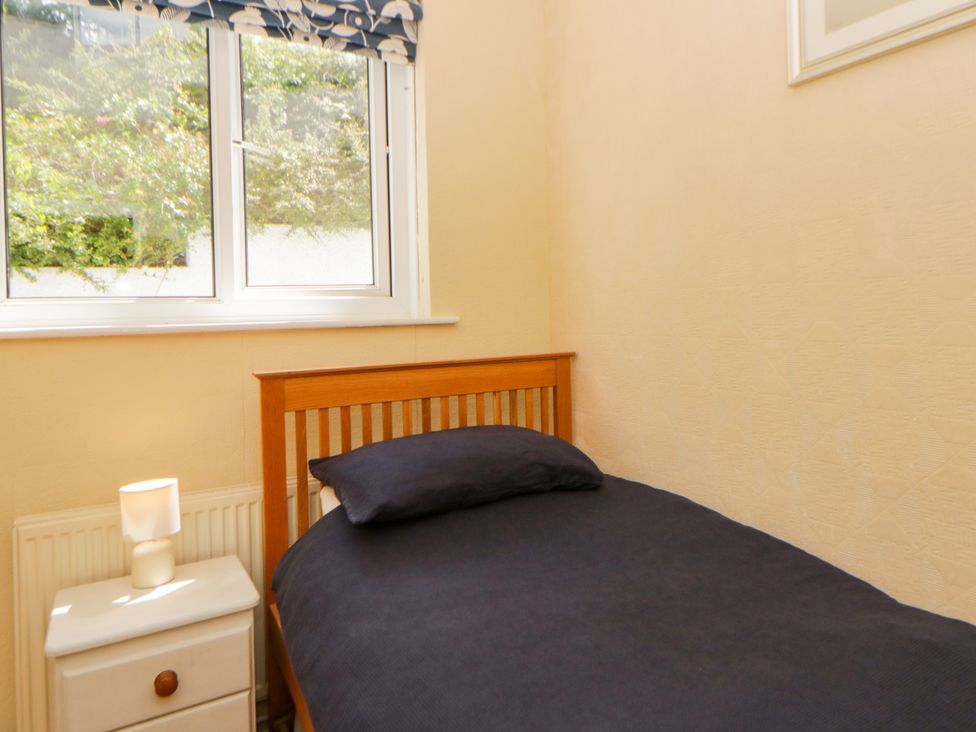 A bedroom with a single bed and a window at Delyn Aur Tresaith, Ceredigion