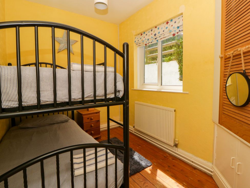 A bedroom with a bunk bed and window at Delyn Aur Tresaith, Ceredigion