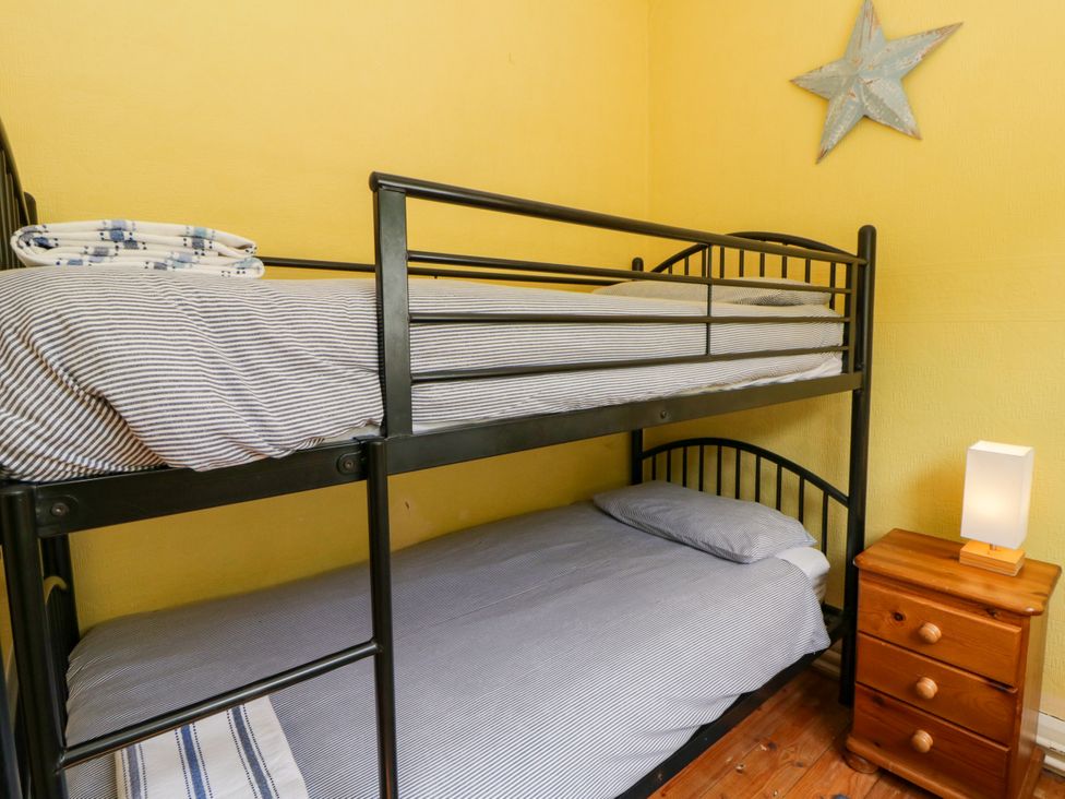 A bunk bed with striped bedding and a lamp at Delyn Aur, Tresaith, Ceredigion