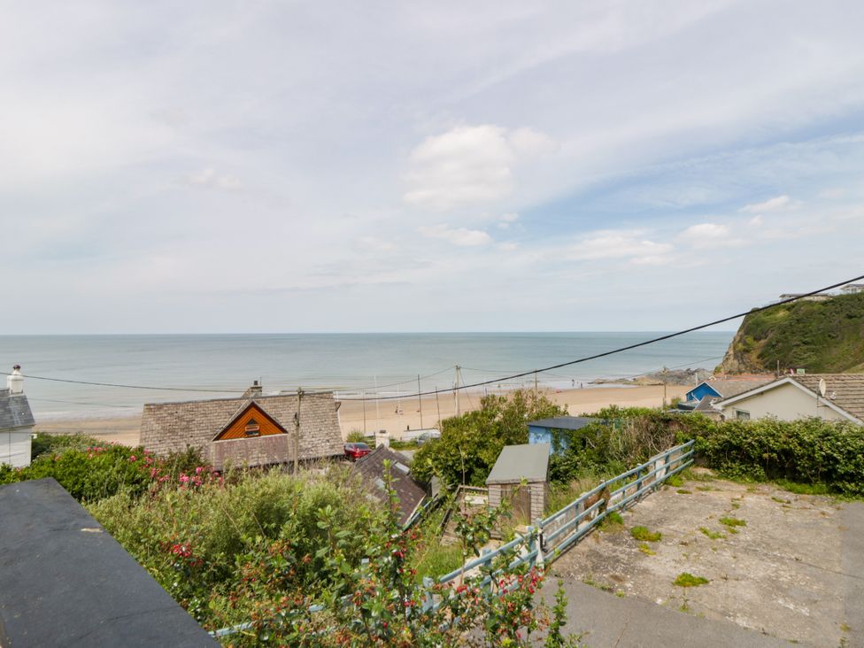 A view of the ocean and beach with houses at Delyn Aur Tresaith, Ceredigion