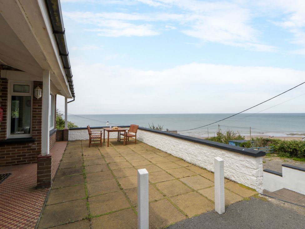A patio area with table and chairs overlooking the sea at Delyn Aur, Tresaith, Ceredigion